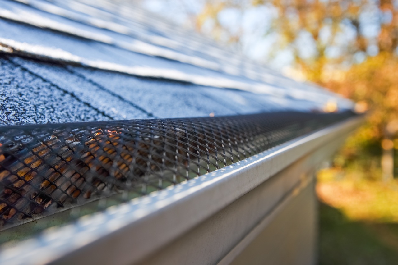 Closeup image of black metal leaf guard on metal gutters installed on black shingled roof-Gutter Installation in Lawson MO