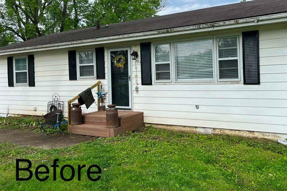 Front view of a white single-story home in Excelsior Springs, MO, without gutters installed, showing exposed roof edges above the entry and windows.