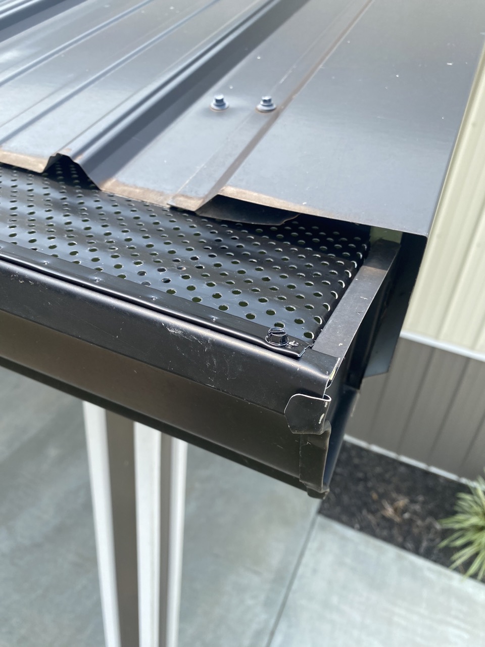 Close-up view of Black aluminum gutters with gutter guard installed on metal roof